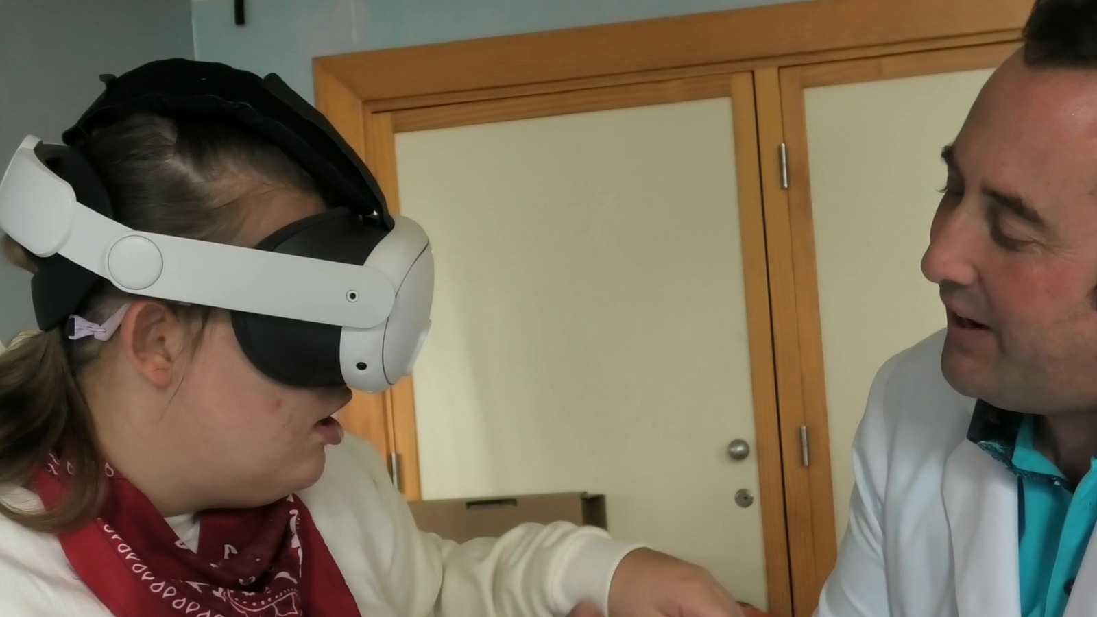 Una alumna de Ciudad San Juan de Dios usa unas gafas de realidad virtual mientras Antonio Moral, maestro de Educación Especial, la acompaña