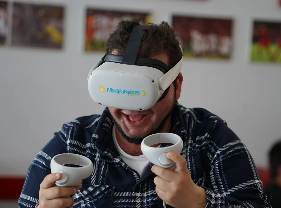 Un participante sonríe mientras maneja los dos mandos en una experiencia de realidad virtual de Minifunkids