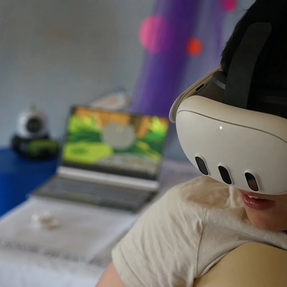 Una persona con las gafas de realidad virtual de Minifunkids durante una sesión, con la experiencia en marcha en la pantalla del portátil de al lado