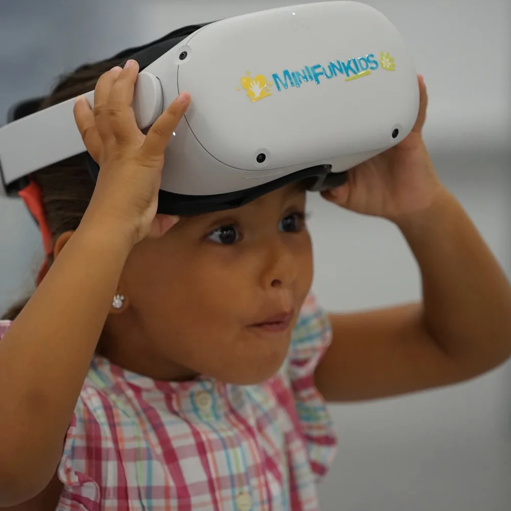 Una niña se sujeta con las dos manos las gafas de realidad virtual de Minifunkids mientras descubre la experiencia
