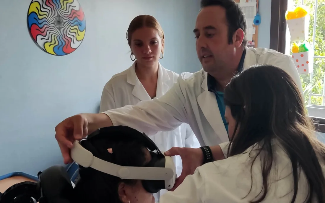 Varios profesionales de un centro ajustan las gafas de realidad virtual de Minifunkids a una usuaria durante una sesión