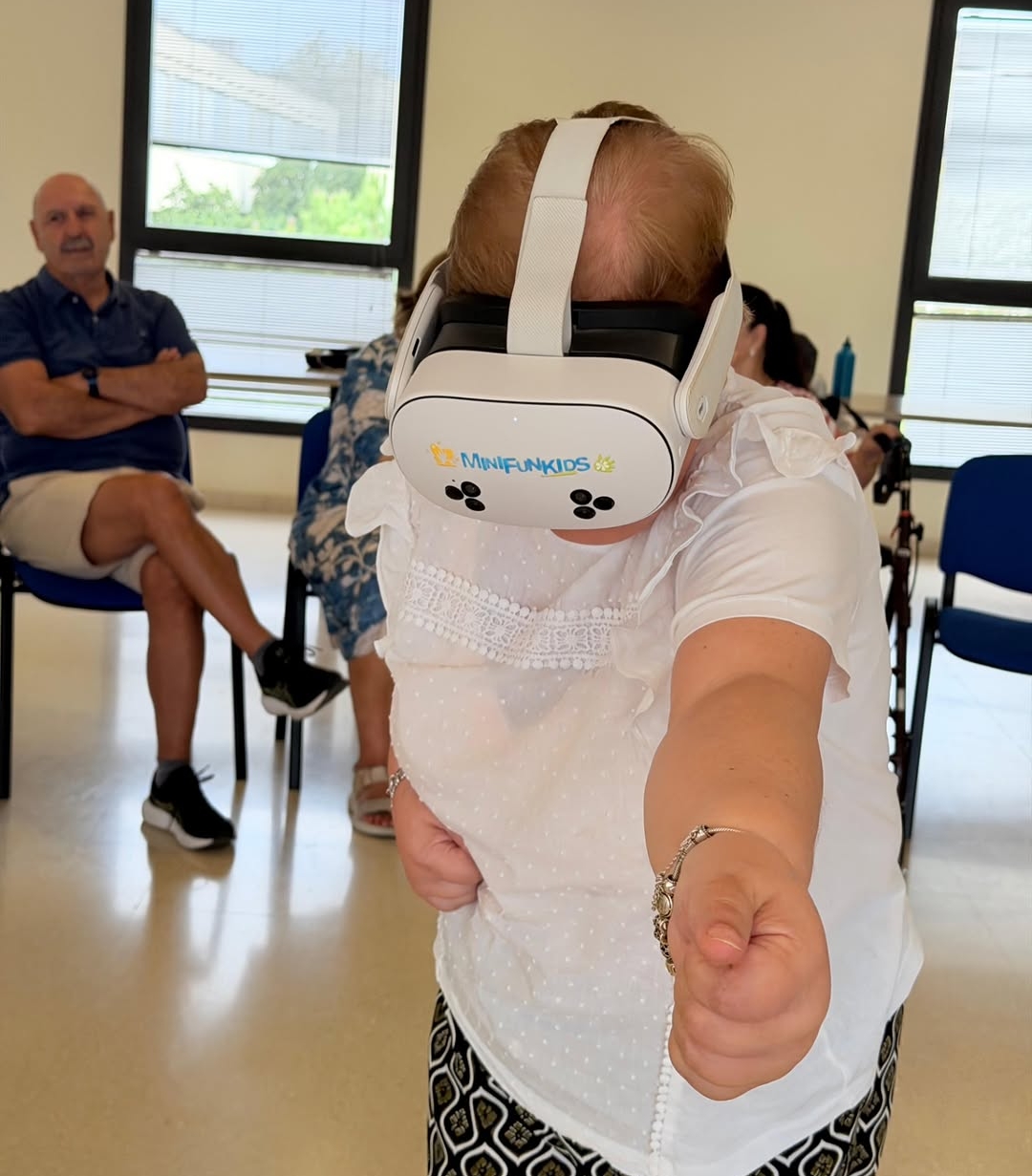 Mujer mayor con gafas de realidad virtual extiende el brazo durante el taller de Jerez